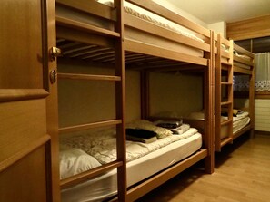 A bunk bed room with a wooden door and a window with curtains. - Thea, (Grächen), 1021 by Interhome (Grächen)