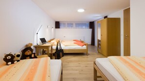 Una camera da letto con due letti, una scrivania con un portatile, una sedia, un armadio e una finestra con tende.