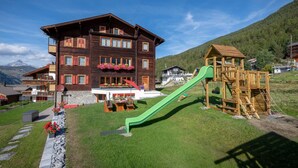 Un edificio in legno con balconi, uno scivolo verde e un'area giochi.