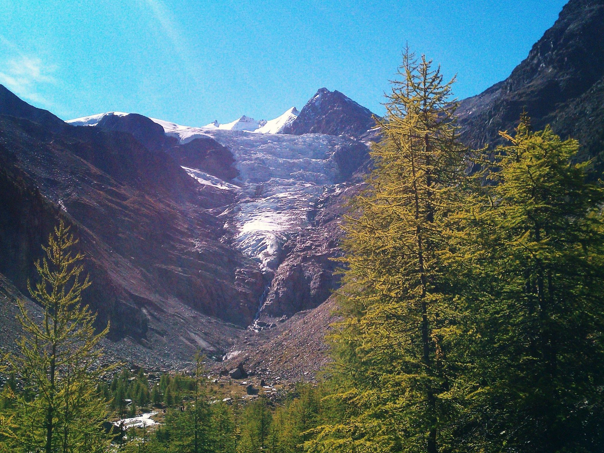 A mountainous landscape with a valley, trees, and a clear sky.