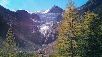 A mountainous landscape with a valley, trees, and a clear sky.