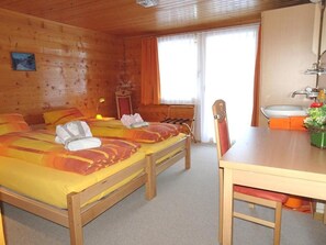 A wooden cabin room with two beds, a table, and a bathroom. - Sunnegga, (Grächen), by Interhome (Grächen)