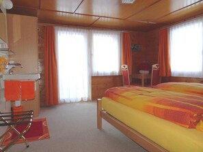 Ein Schlafzimmer mit Bett, Schreibtisch, Stuhl und einem Fenster mit Vorhängen.