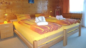 Une chambre rustique en bois avec deux lits, une table de chevet, une lampe et un tableau au mur.