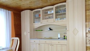 Une cuisine avec des meubles de rangement en bois, un plan de travail et une chaise.