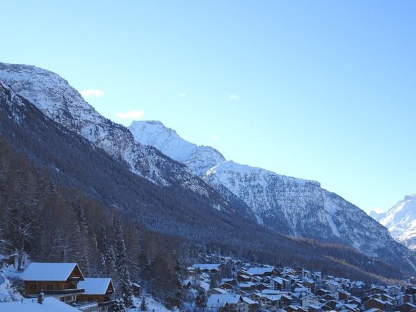 Un village de montagne enneigé, avec des maisons en bois et une montagne imposante en arrière-plan.