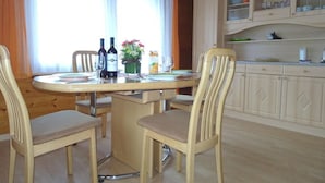 Un coin repas avec une table ronde, des chaises et une cuisine équipée d’armoires.