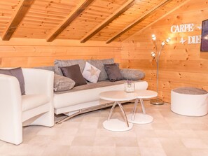 A cozy room with a wooden ceiling, a white sofa with cushions, a small round table, and a white ottoman. - Kelly, (Grächen), 2065 by Interhome (Grächen)
