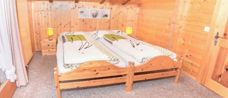 A wooden room with a bed, two bedside lamps, and a ceiling light.