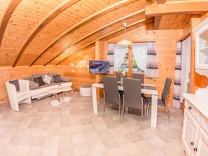 A cozy, wooden interior with a dining area, sofa, and a flat-screen TV mounted on the wall. - Kelly, (Grächen), 2065 by Interhome (Grächen)
