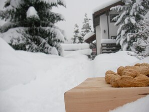 A wooden table with walnuts in a snowy outdoor setting. - Ferienwohnungen Goldblick, (Grächen), 1767+1034+2083 by Interhome (Grächen)