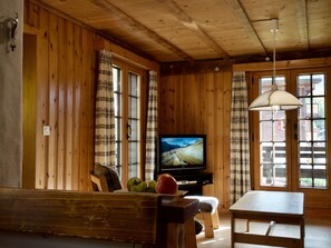 Een houten interieur met een televisie op een standaard, een bankje en een tafel.