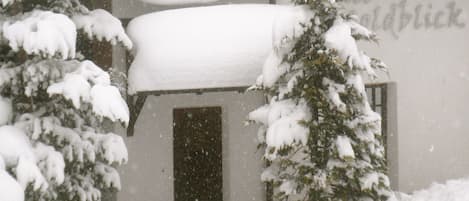 Un edificio con árboles cubiertos de nieve y una puerta visible.