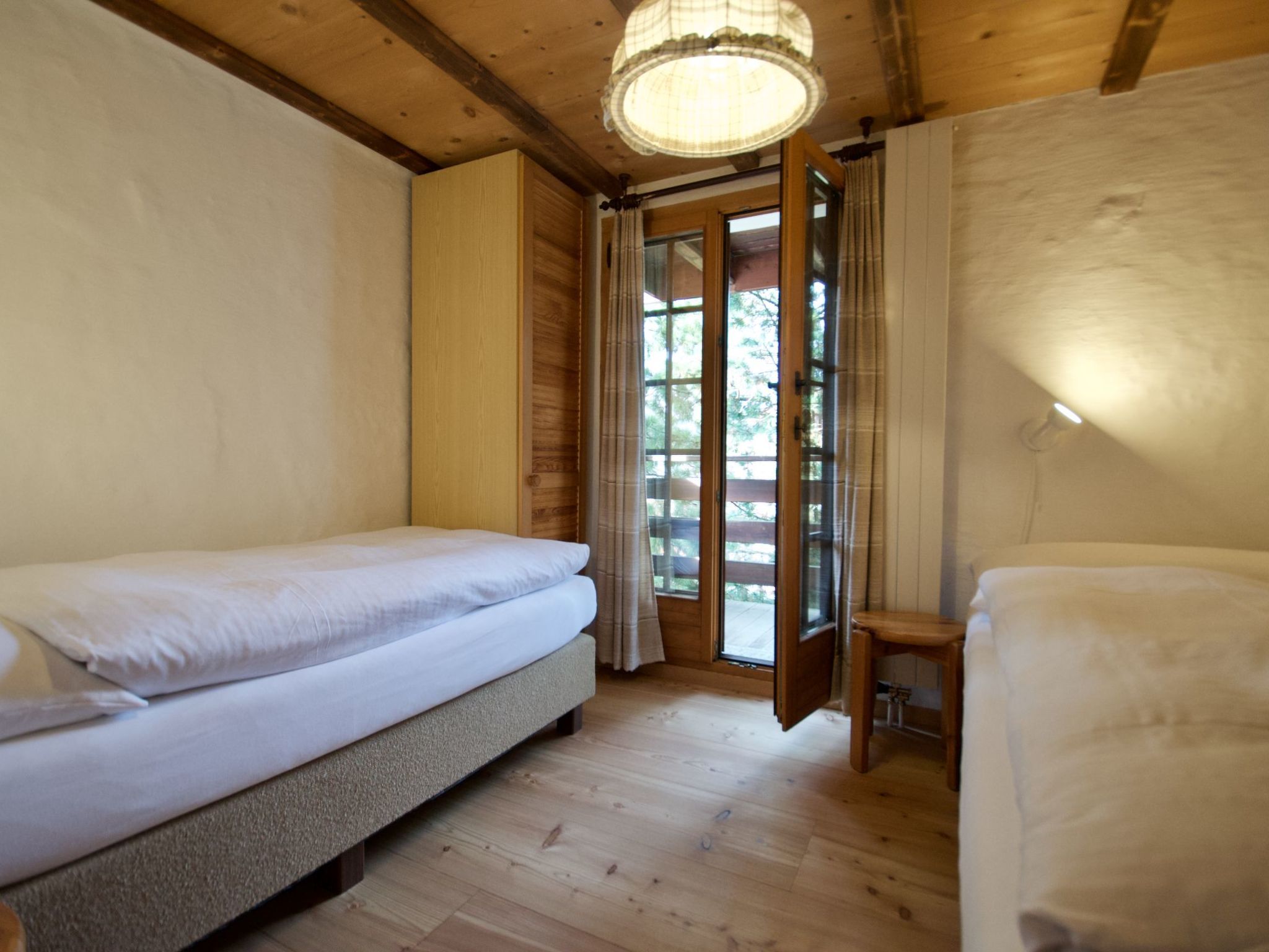 Une pièce avec un lit, une petite table et une fenêtre avec des rideaux.