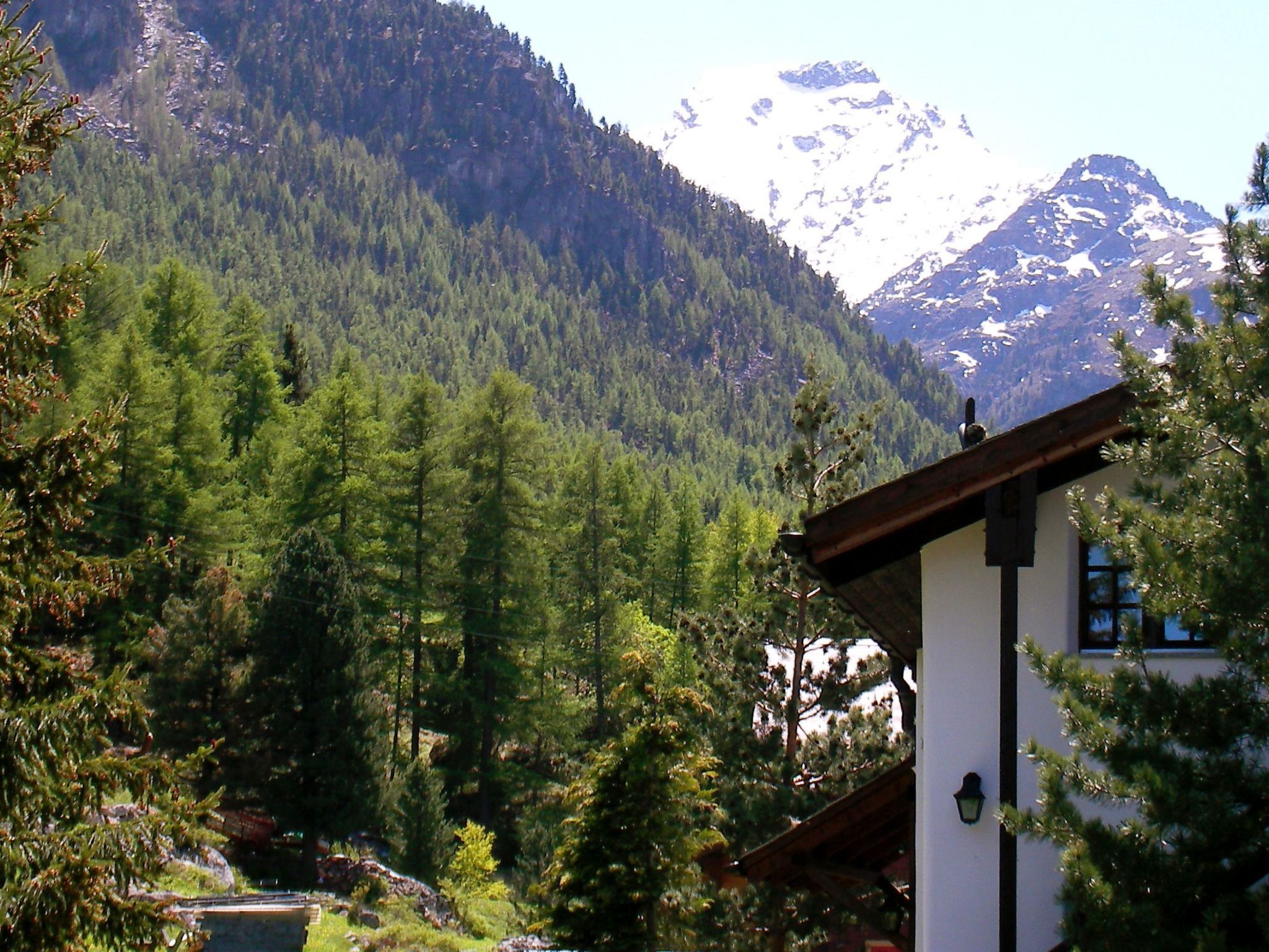 A mountain landscape with a building featuring a sloped roof and a window with a light fixture.
