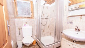Ein Badezimmer mit Toilette, Dusche, Waschbecken und Holzboden.