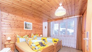 Ein Zimmer mit Holzvertäfelung, einem Bett, einem Nachttisch und einem Fenster mit Vorhängen.