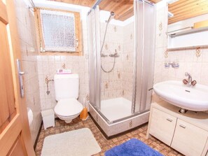 A bathroom with a toilet, shower, sink, and a window. - Ferienwohnungen Fleurs des Alpes, (Grächen), by Interhome (Grächen)