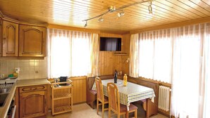 A wooden cabin interior with a kitchen, dining area, and a TV mounted on the wall. - Bergtreu, (Grächen), by Interhome (Grächen)