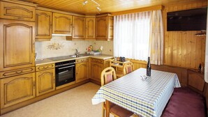 A wooden kitchen with a dining table, chairs, and a built-in oven. - Bergtreu, (Grächen), by Interhome (Grächen)