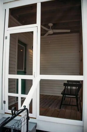 A screened porch with a ceiling fan, a door, and a chair. - The Little Retreat Unit A - Walk to Shops & Beach (Cape Charles)