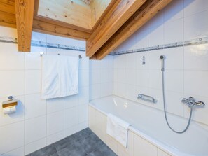 Ein Badezimmer mit einer Badewanne, einer Dusche und einer Holzbalkendecke.