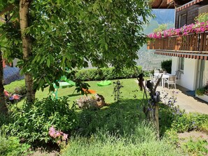 A garden with a wooden deck, a dining area with chairs, and a view of mountains. - Schneevogul, (Grächen), 1114 by Interhome (Grächen)
