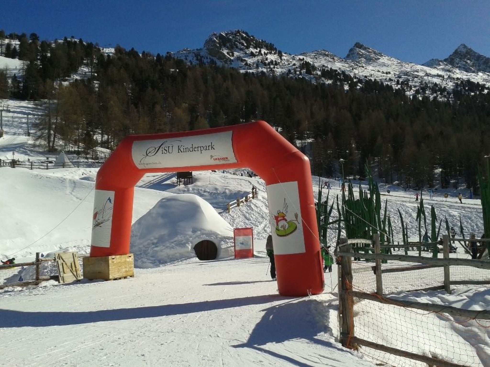 A ski resort entrance with a red archway and a sign that reads 'SiSU Kinderpark.'