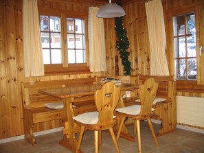 Ein Holzinterieur mit einer Bank, Stühlen, großen Fenstern und einem Weihnachtsbaum.