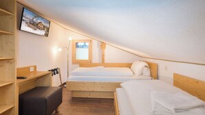 A dormitory room with two beds, a desk, a bench, and a TV on the wall. - Lunic, AZapartments.ch, B&B, (Grächen), 1057 by Interhome (Grächen)