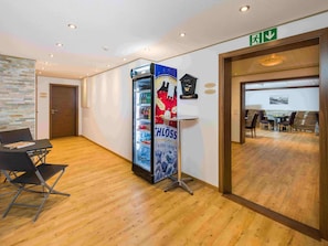A hotel lobby with a seating area, a refrigerator with beverages, and a sign indicating an exit. - Ferienwohnungen Lunic, AZapartments.ch, B&B, (Grächen), 1057 by Interhome (Grächen)