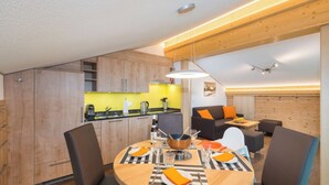 A modern kitchen with wooden cabinets, a dining area with a round table, and a living space with a sofa and a coffee table. - Lunic, AZapartments.ch, B&B, (Grächen), 1057 by Interhome (Grächen)