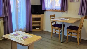 Een kamer met een televisie, houten meubels en paarse gordijnen.