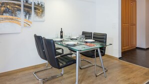 A modern dining area with a glass table, black leather chairs, and a wooden floor. - AsterB, (Grächen), by Interhome (Grächen)