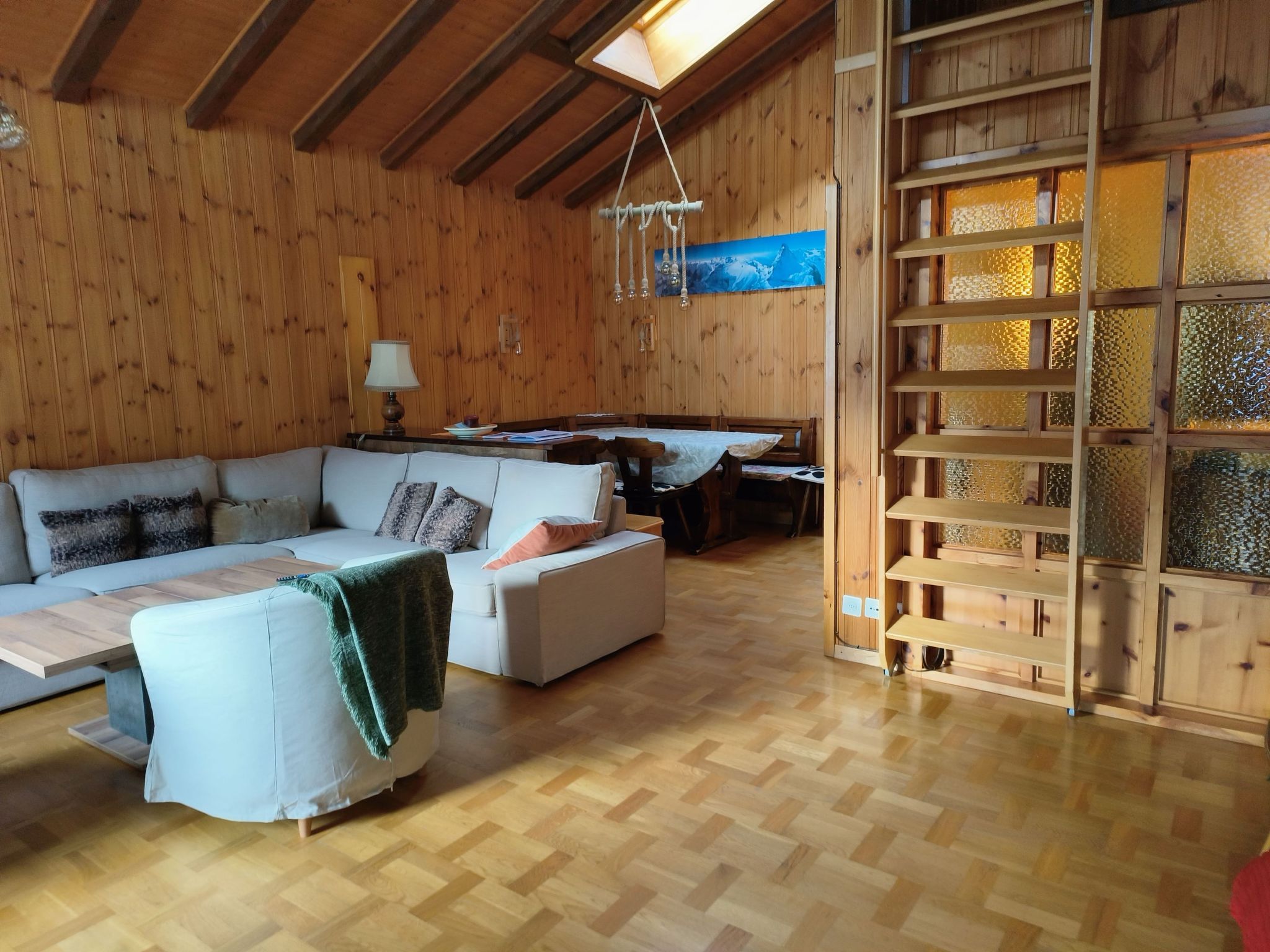 Een gezellige woonkamer met houten details, een zithoek, een eettafel en een bijenkorfdecoratie.