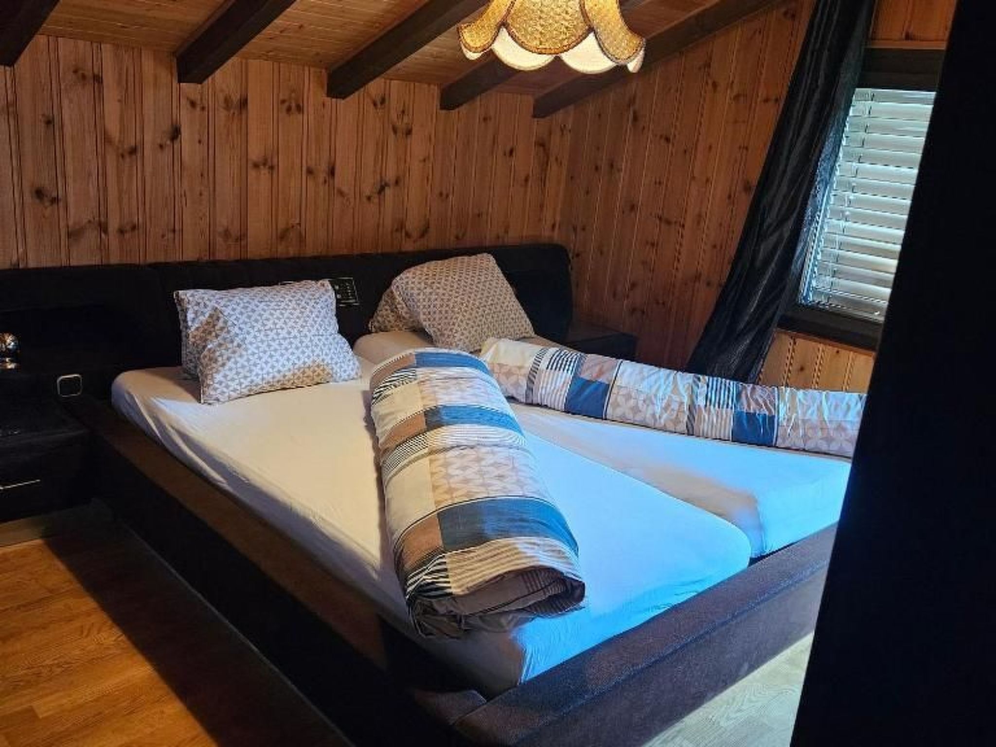 A wooden-paneled room with a bed, pillows, and a nightstand.