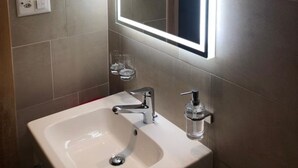 A bathroom with a white sink, a mirror, and a hand soap dispenser. - Alpfrieden, (Grächen), 1336 by Interhome (Grächen)