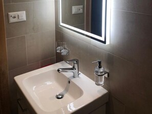 Ein Badezimmer mit einem weißen Waschbecken, einem Spiegel und einer Handseifen-Spender.