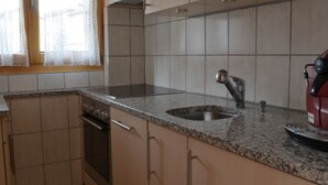 A kitchen with a granite countertop, stainless steel sink, and a red appliance. - Alpfrieden, (Grächen), 1336 by Interhome (Grächen)