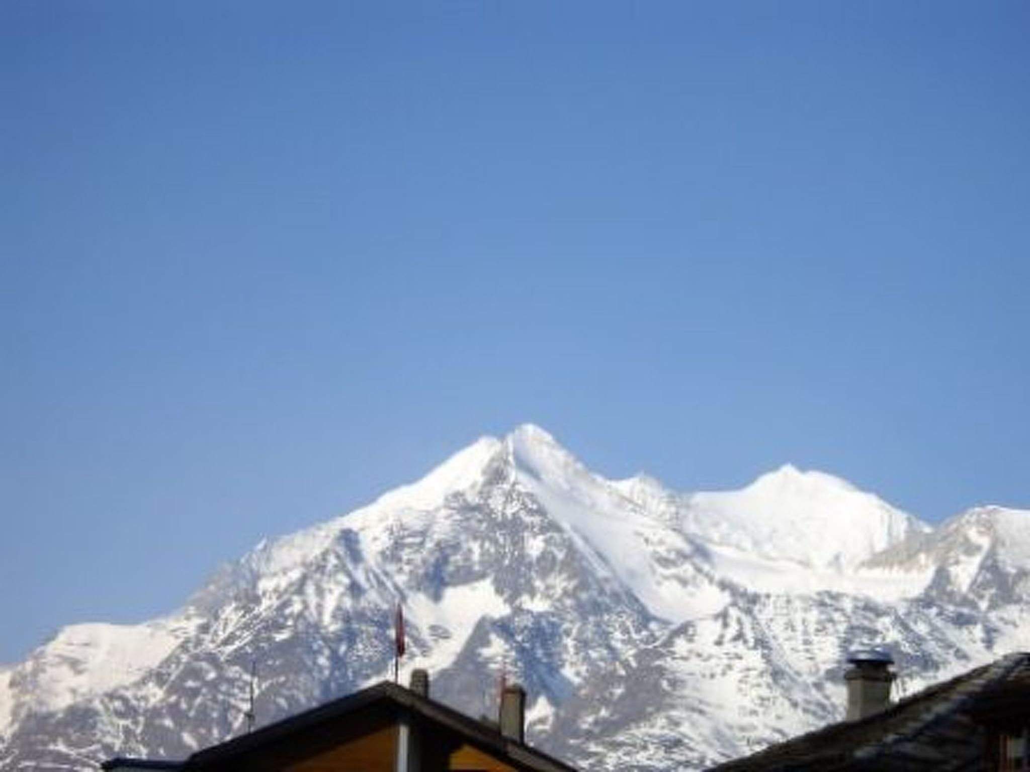 Pico de montanha coberto de neve sob céu claro.