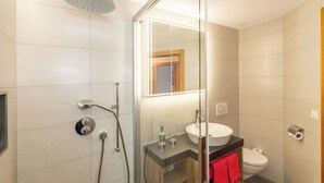Ein modernes Badezimmer mit Duschkabine aus Glas, Waschbecken und Toilette.