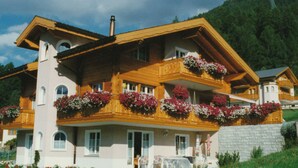 Ein mehrstöckiges Holzhaus mit Balkonen, einem Schornstein und Blumenkästen.