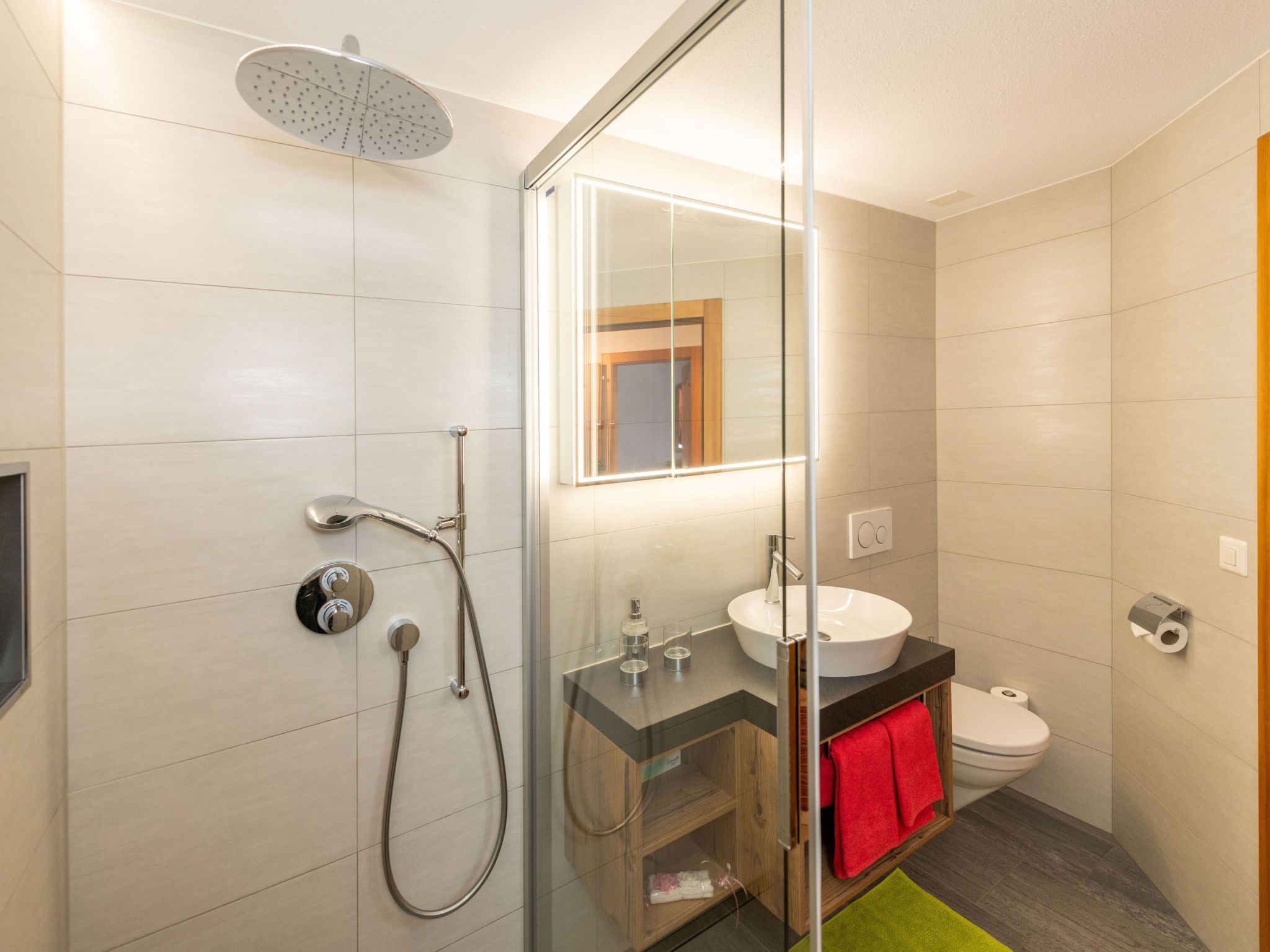 Un baño moderno con cabina de ducha de vidrio, un lavabo y un inodoro.