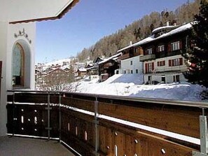 A snow-covered mountain village with traditional buildings, a wooden balcony, and a clear sky. - Sunstar 10, (Grächen), 1020 by Interhome (Grächen)
