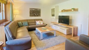 Una sala de estar con sofá, mesa de centro, televisor y un cuadro en la pared.