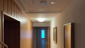 Un pasillo con paneles de madera, una lámpara en el techo y una puerta al final.