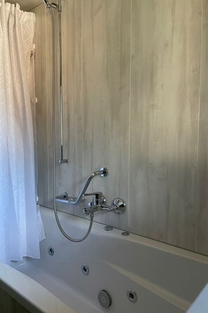 A bathroom with a shower, a bathtub, and a curtain. - Ferienwohnungen Miranda, (Grächen), by Interhome (Grächen)