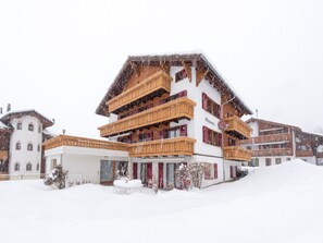A multi-story hotel with wooden balconies and a snow-covered landscape. - Ferienwohnungen Miranda, (Grächen), by Interhome (Grächen)