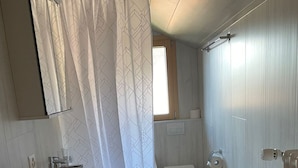 A compact bathroom with a sink, toilet, and shower curtain. - Ferienwohnungen Miranda, (Grächen), by Interhome (Grächen)