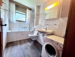 A bathroom with a toilet, sink, and washing machine. - Metropol B28, (Grächen), by Interhome (Grächen)